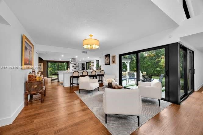 Open-concept interior featuring wood-finish flooring, floor-to-ceiling sliding glass doors, center island with stone countertop, and recessed lighting