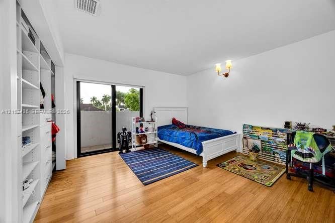 Wood-finish flooring, custom built-in closet shelving, sliding glass door, and wall-mounted dual-bulb light fixture