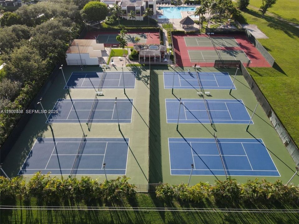 Recreational facility featuring six hard-surface tennis courts, fenced perimeter, and lighting infrastructure