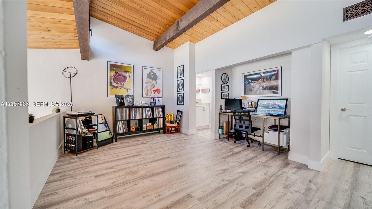 Vaulted wood-plank ceiling with exposed structural beams and light-toned wood-finish flooring