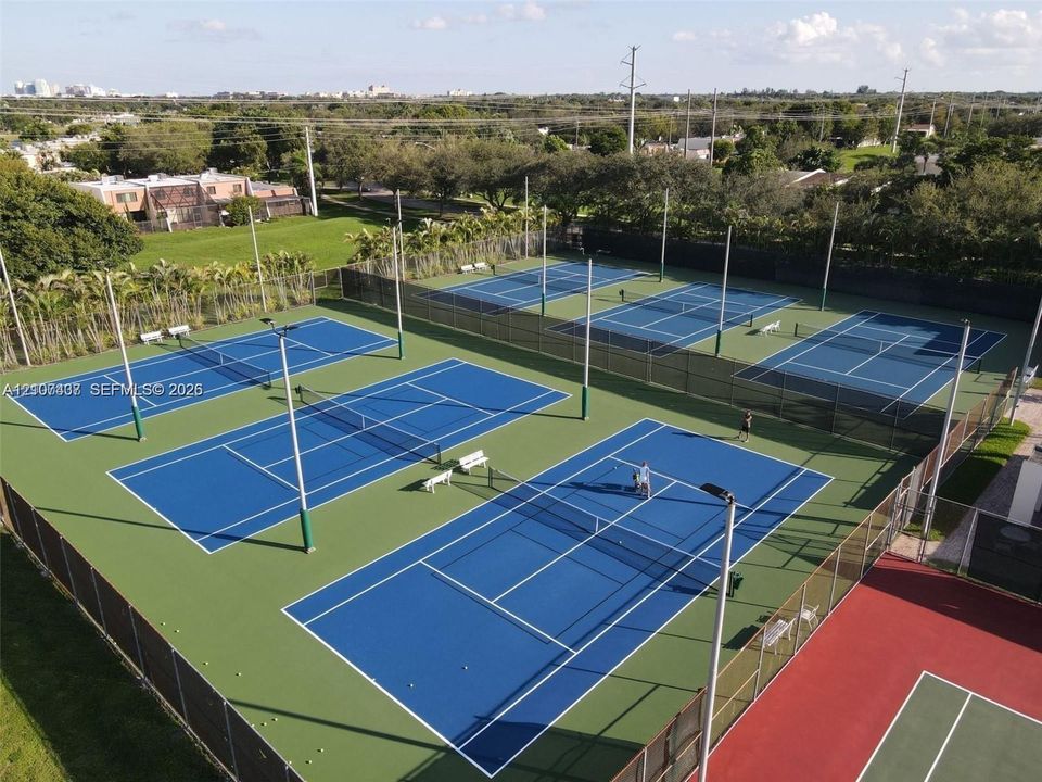 Multi-court tennis facility featuring high-tension perimeter fencing, floodlighting, and hard-surface playing areas
