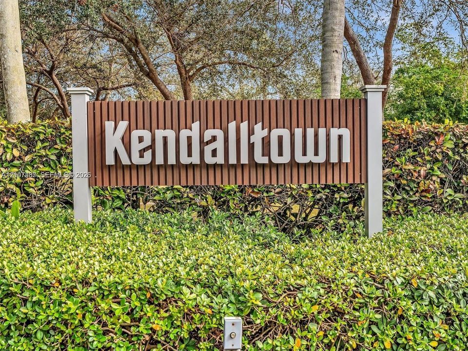 Community monument sign featuring dimensional lettering set against a slatted wood-finish panel, framed by white support pillars and manicured shrubbery