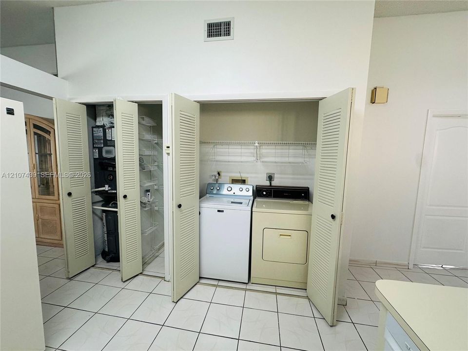 Laundry area featuring louvered bi-fold closet doors, built-in wire shelving, and tile flooring