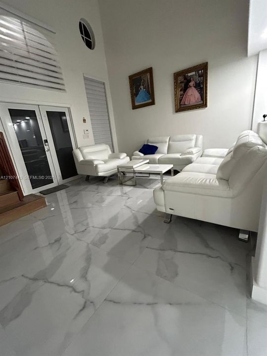Stucco exterior featuring a covered patio, stone-tiled pool deck, in-ground swimming pool, and concrete perimeter wall