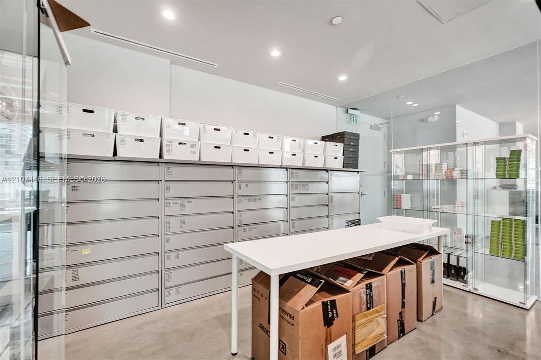 Industrial-style space featuring polished concrete flooring, recessed ceiling lighting, wall-to-wall integrated metal cabinetry, and full-height glass display shelving