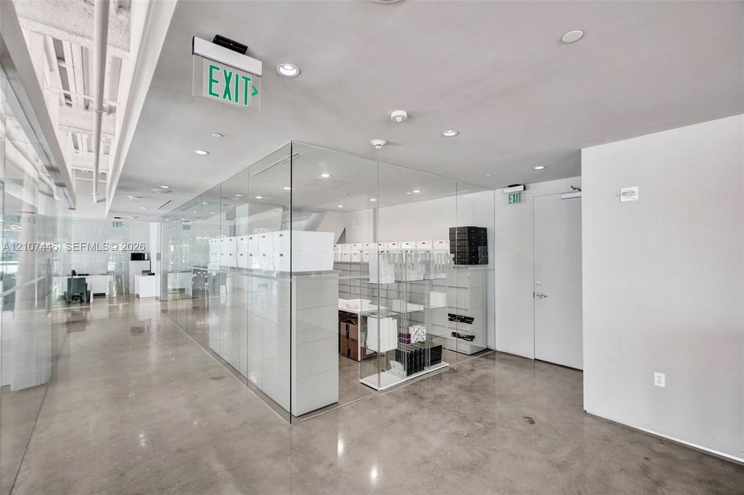 Polished concrete flooring, floor-to-ceiling glass wall partitions, recessed ceiling lighting, and exposed structural ceiling elements