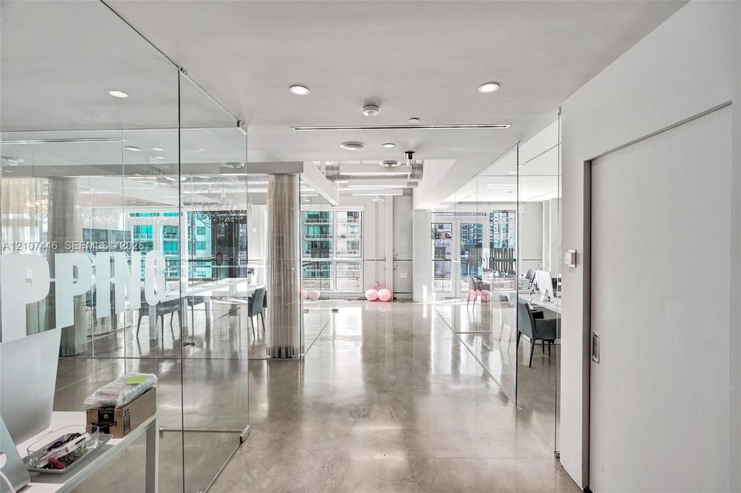 Polished concrete flooring, floor-to-ceiling glass partition walls, recessed lighting, and expansive windows