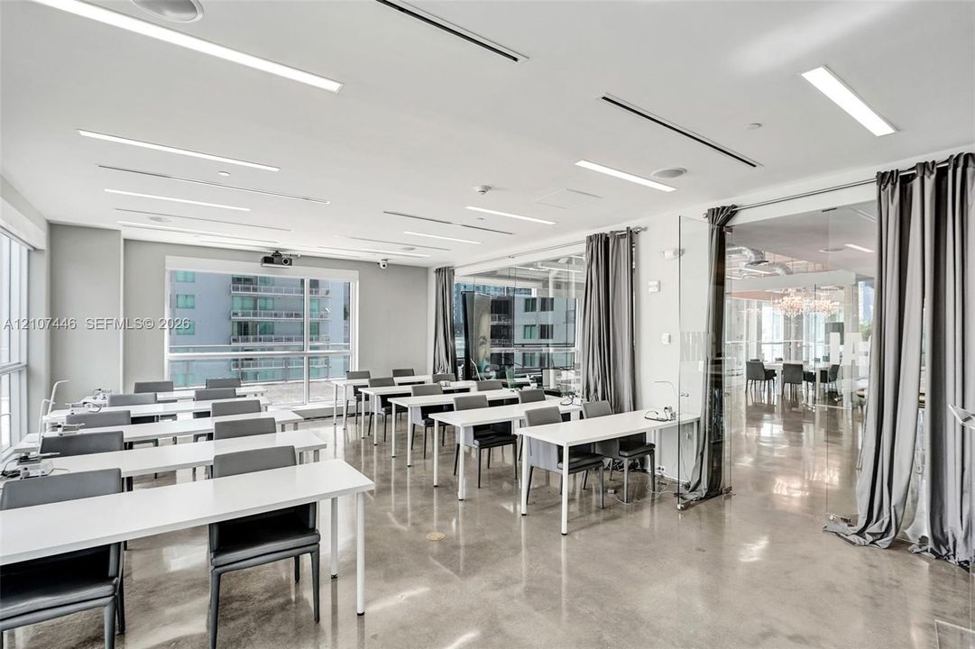 Open-concept room featuring polished concrete flooring, linear recessed lighting, floor-to-ceiling glass windows, and a glass-enclosed partitioned space