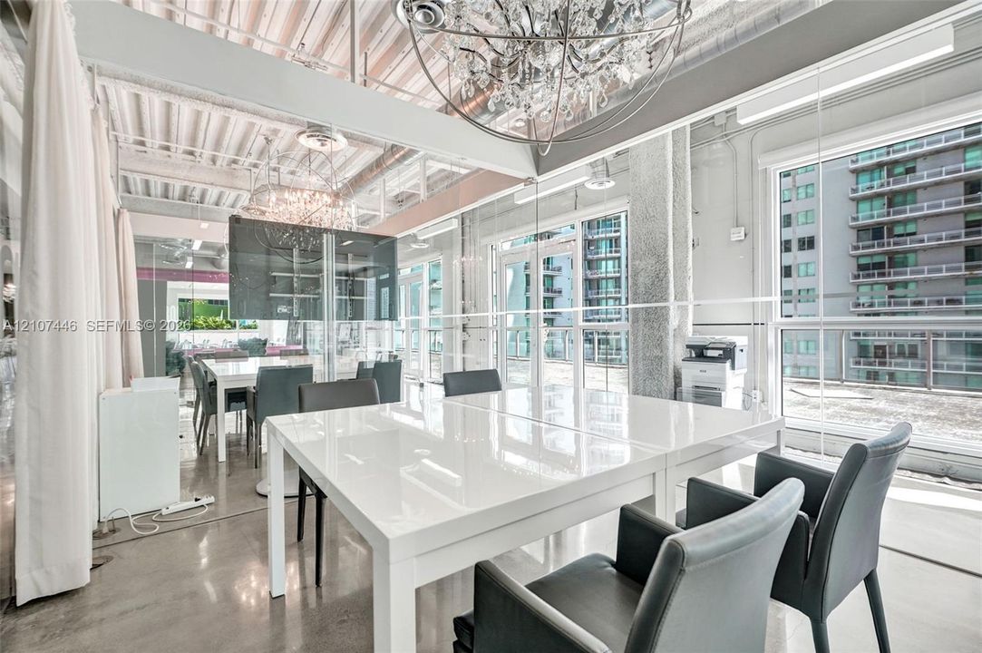 Industrial-style interior featuring exposed corrugated metal ceiling, expansive glass curtain walls, polished concrete flooring, and oversized crystal sphere chandeliers