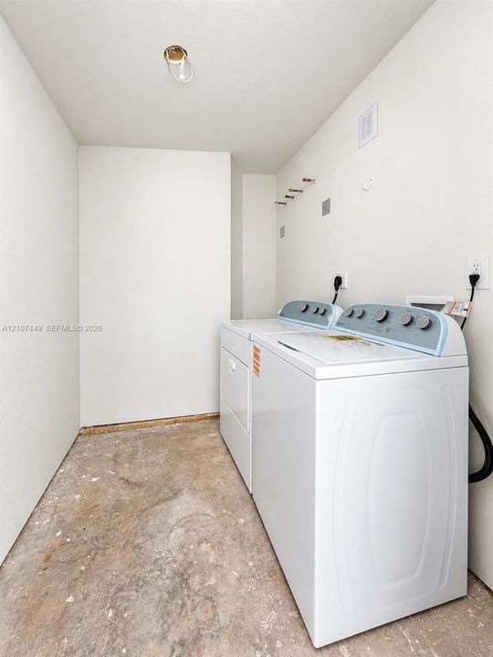 Dedicated utility space featuring washer and dryer hookups, overhead lighting, and concrete flooring
