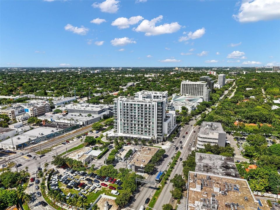 Aerial perspective of a multi-story concrete structure featuring glass balcony railings and floor-to-ceiling exterior glazing