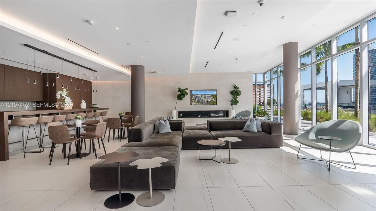 Floor-to-ceiling windows, linear built-in fireplace, tile flooring, recessed ceiling lighting, and custom wood-finish cabinetry