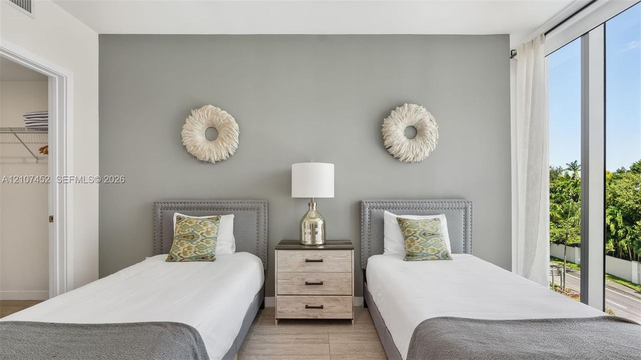 Room featuring floor-to-ceiling windows, neutral wall paint, tile flooring, and a walk-in closet with built-in shelving