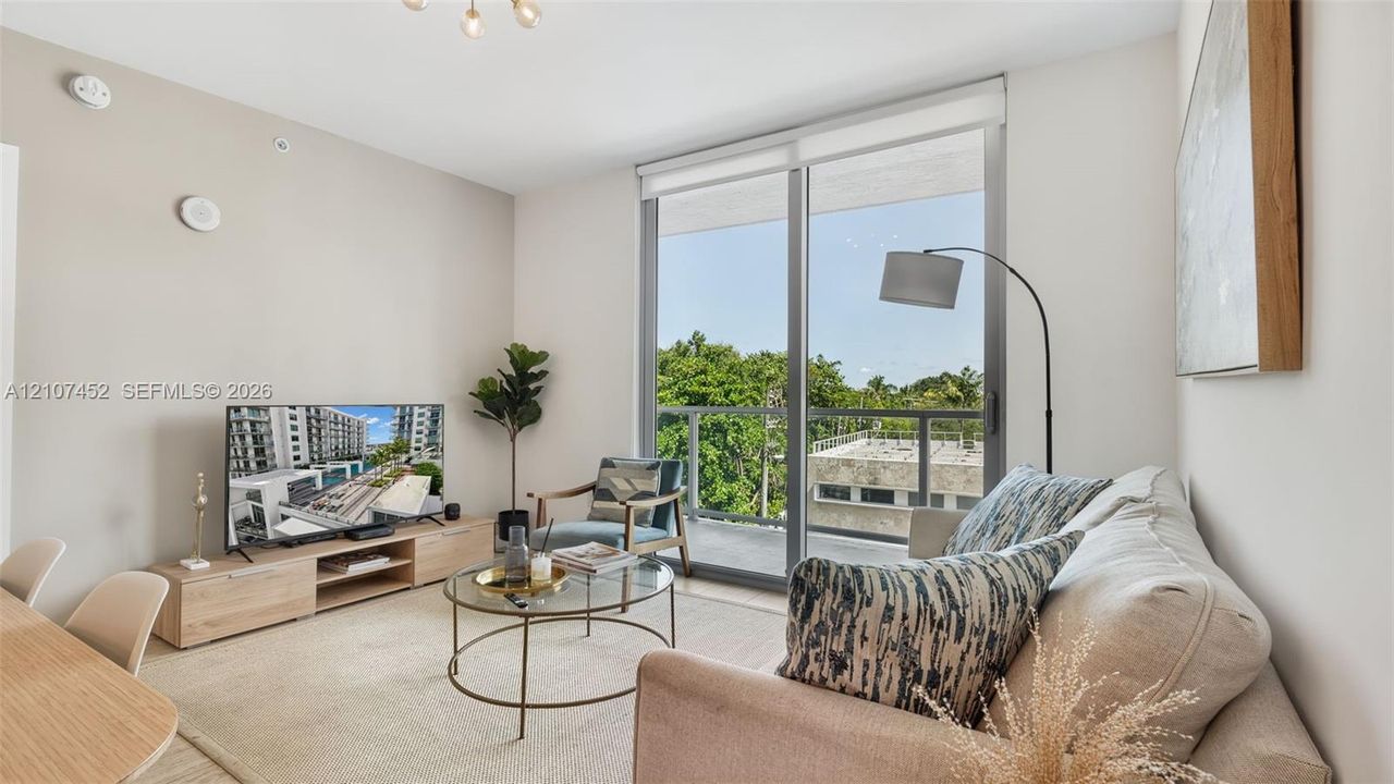 Living area featuring floor-to-ceiling glass sliding doors, private balcony access, and neutral interior finishes