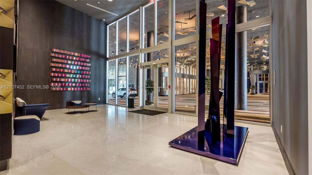 Grand entrance featuring expansive floor-to-ceiling glass windows, polished stone flooring, and high ceilings with decorative ceiling installations