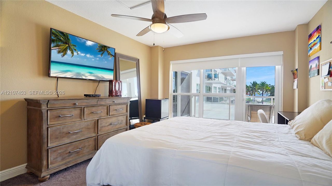 Room featuring a ceiling fan with integrated lighting, carpeted flooring, and glass doors leading to a balcony