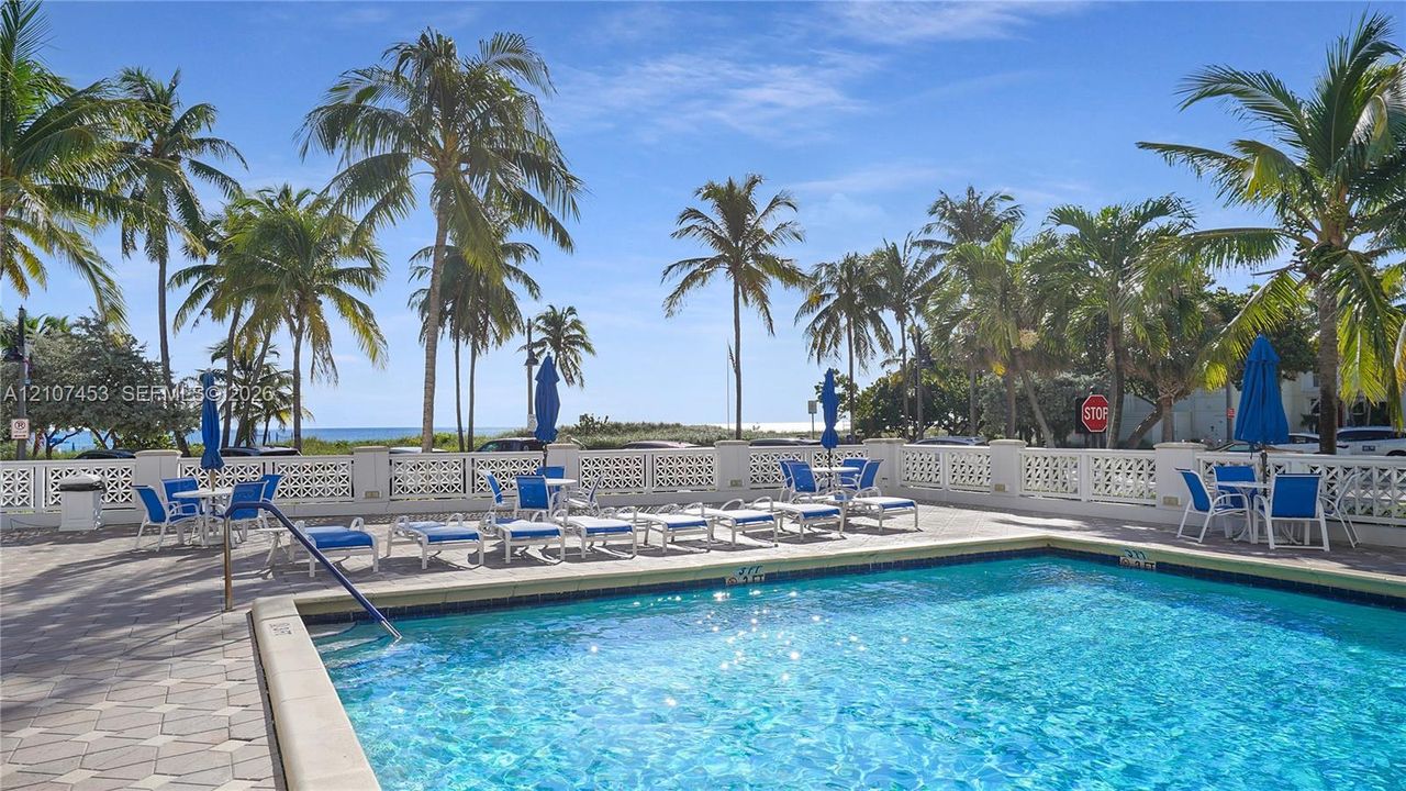 Swimming pool with a tile surround, decorative masonry perimeter wall, and established palm trees