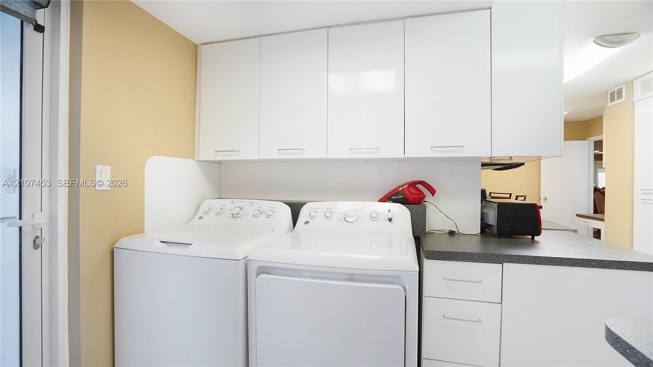Laundry area featuring white cabinetry, solid-surface countertops, and dedicated workspace