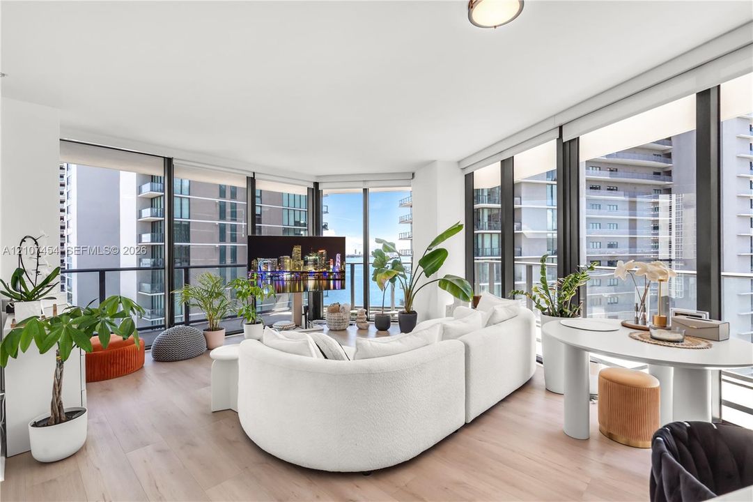 Floor-to-ceiling windows, wood-finish flooring, and wraparound glass balcony railings