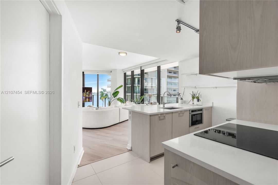 Kitchen featuring light wood-finish cabinetry, white countertops, built-in cooktop, and floor-to-ceiling windows