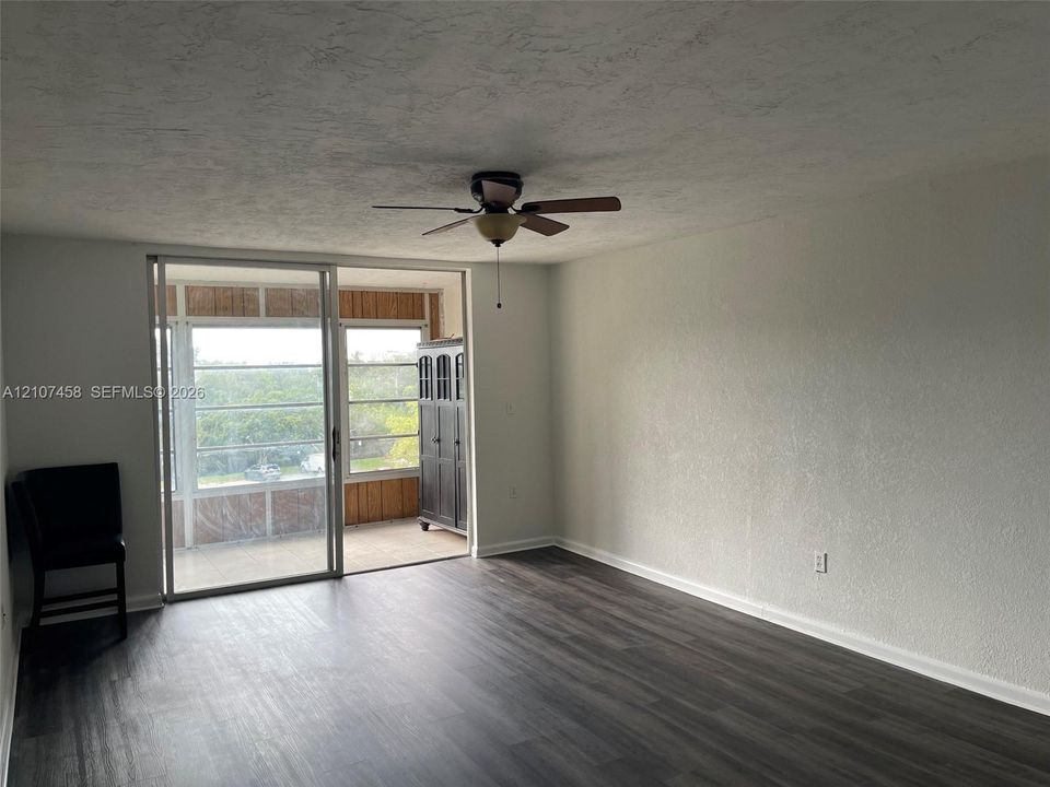 Living area featuring wood-finish flooring, a ceiling fan with integrated lighting, and glass sliding doors