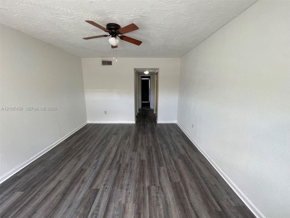 Interior space featuring wood-finish flooring, textured ceilings, and a ceiling fan with light fixture