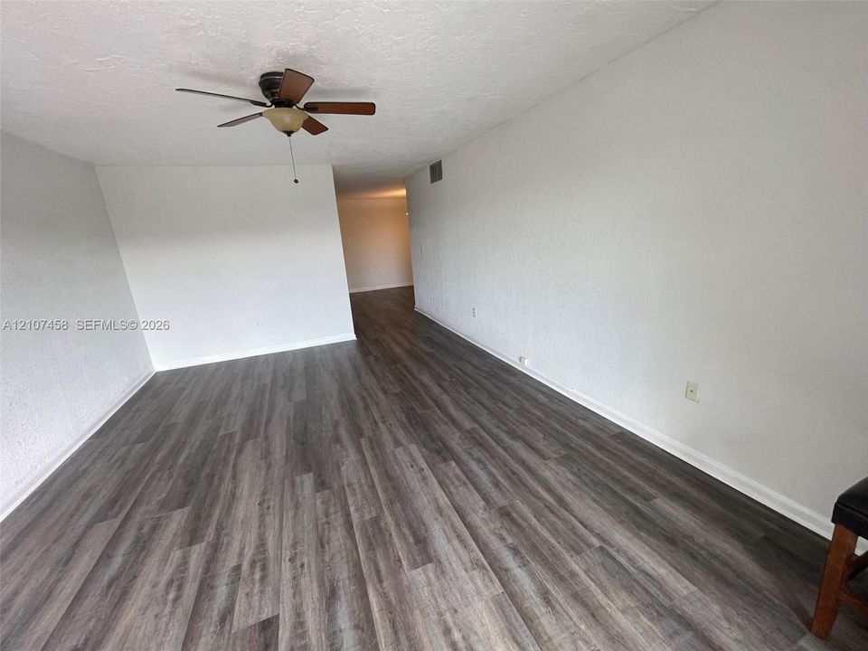 Interior space featuring wood-finish flooring, white walls, and a ceiling-mounted fan with integrated light fixture