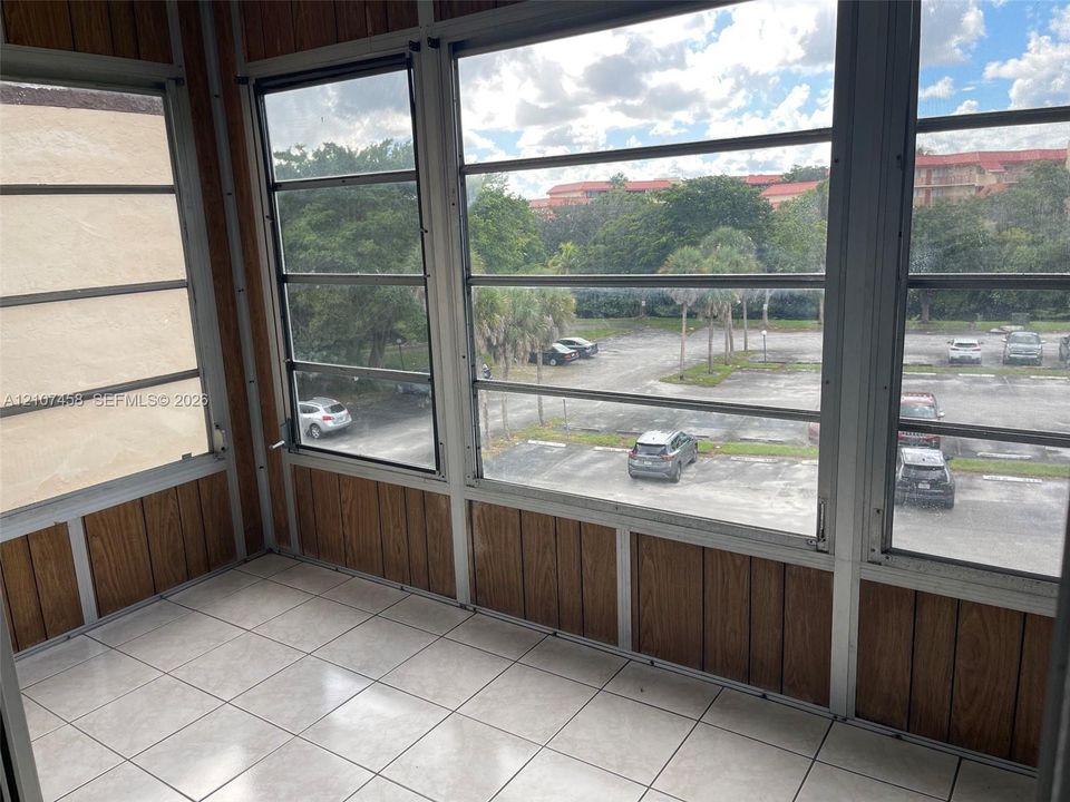 Enclosed porch featuring wood-finish paneling, horizontal sliding windows, and tiled flooring