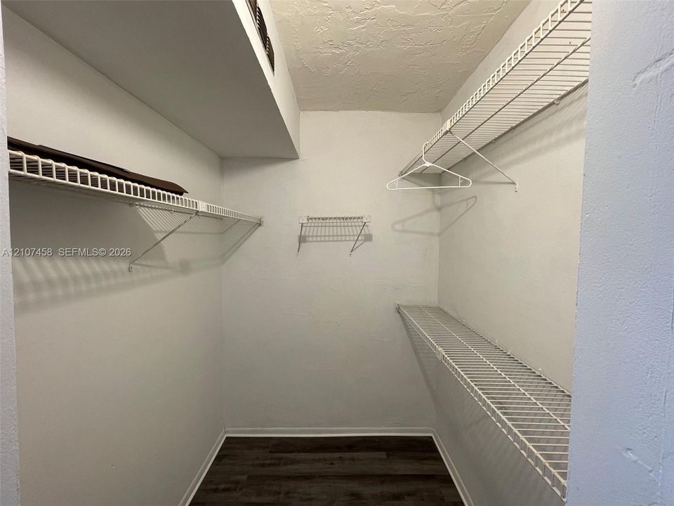 Walk-in storage space featuring wood-finish flooring and tiered white wire shelving