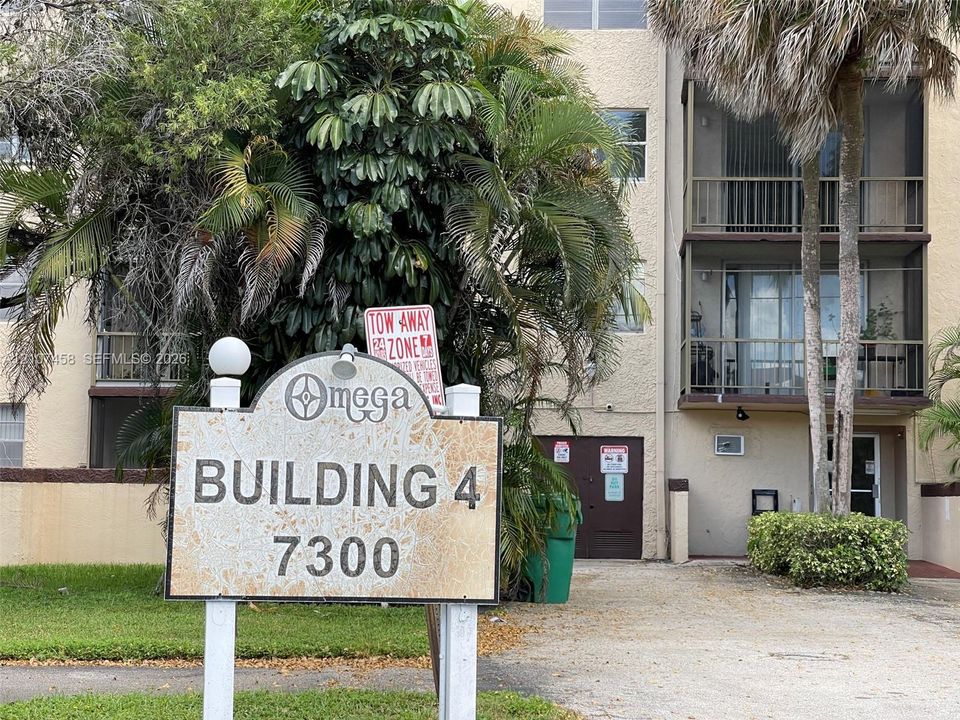 Multi-story building featuring stucco exterior, screened balconies, and mature palm landscaping