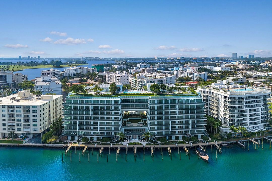 Waterfront mid-rise building featuring a glass-railed rooftop terrace, integrated pool deck, private boat slips, and floor-to-ceiling windows