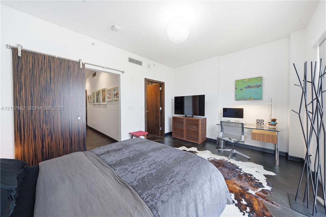Interior space featuring dark tile flooring, a large wood-finish sliding barn door, and a standard swinging door with wood-finish trim