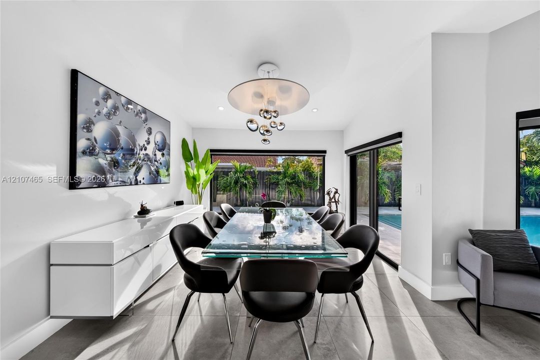 Dining space featuring large-format tile flooring, a modern multi-pendant light fixture, and black-framed sliding glass doors