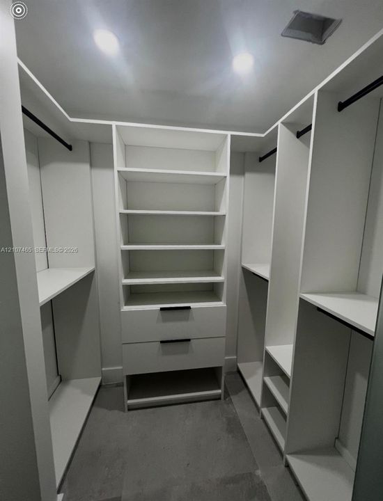 Custom reach-in closet featuring white built-in shelving, dual soft-close drawers with matte black hardware, and integrated hanging rods
