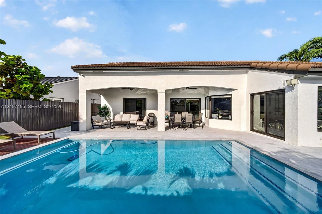 Rear exterior featuring a covered patio, rectangular swimming pool with built-in steps, tile roofing, and sliding glass door access