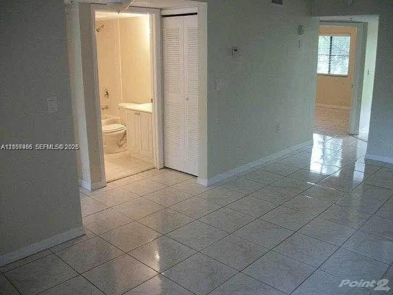 Glossy tile flooring, bifold closet doors, and a bathroom featuring a vanity cabinet with integrated sink