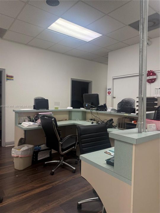 L-shaped reception counter with a light-toned surface and wood-finish flooring