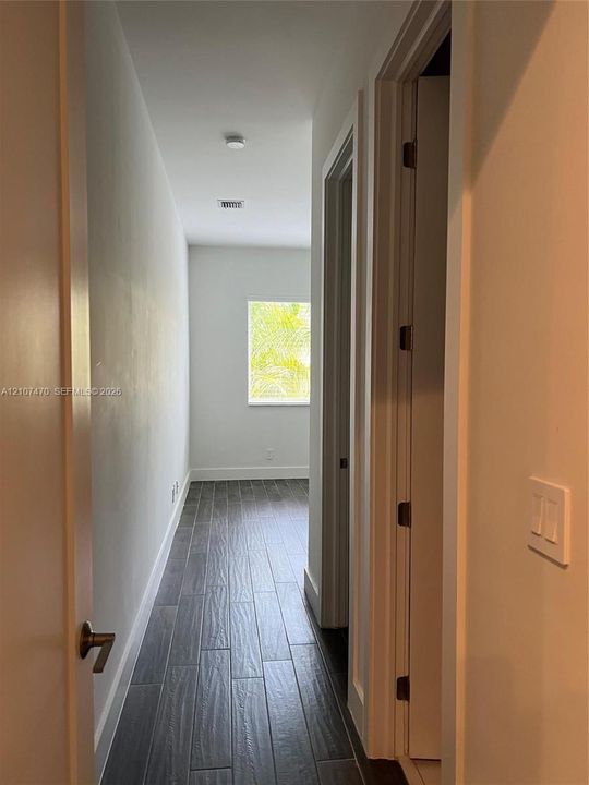 Hallway featuring neutral-toned walls, wood-finish flooring, and a single window