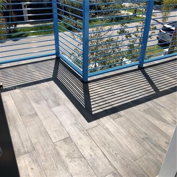Outdoor deck featuring wood-finish tile flooring and a blue horizontal metal railing