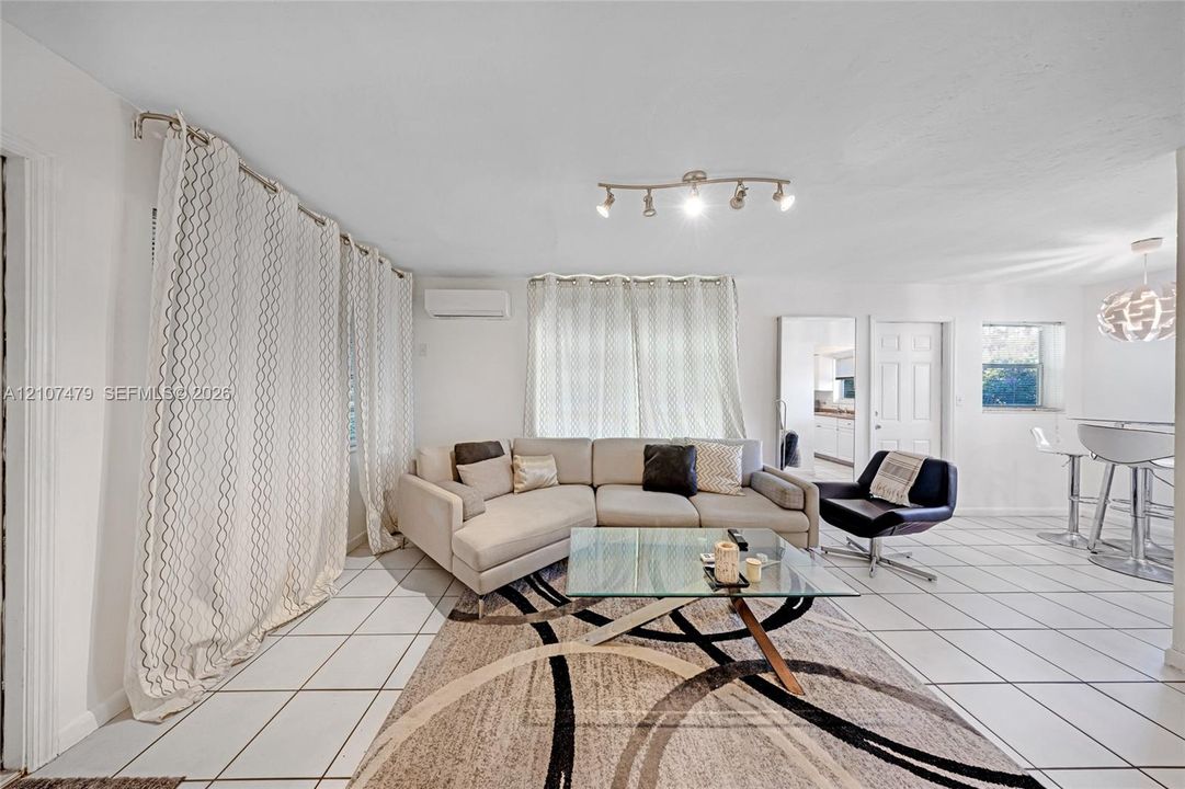 Cottage / guest house, Open living area featuring large-format tile flooring, adjustable track lighting, and a wall-mounted ductless climate control unit