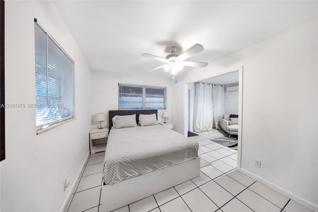 Cottage guest house, Interior space featuring large-format ceramic floor tiling, white walls, two windows with integrated blinds, and a central ceiling fan with integrated light fixture