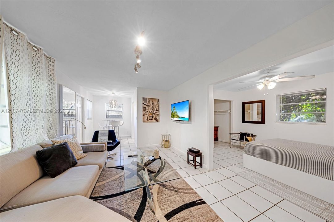 Cottage / guest house, Living room and bedroom space, Ceramic tile flooring, multi-directional ceiling track lighting, ceiling fan with integrated light fixture, and large rectangular windows