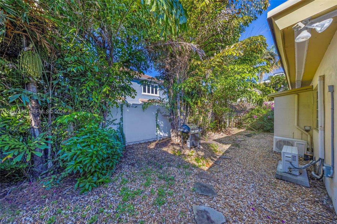 Cottage guest house, Side yard area featuring gravel ground cover, natural stone paver pathway, and mature tree landscaping