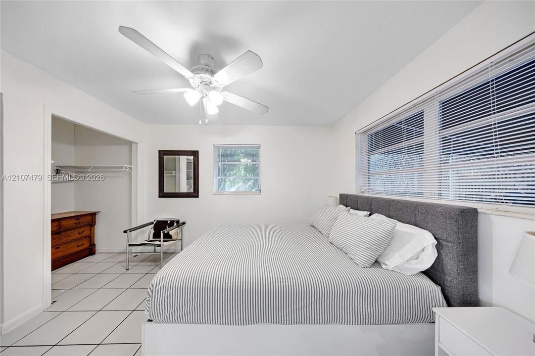 Cottage guest house, Interior space featuring white ceramic tile flooring, a multi-blade ceiling fan with integrated lighting, and horizontal window blinds
