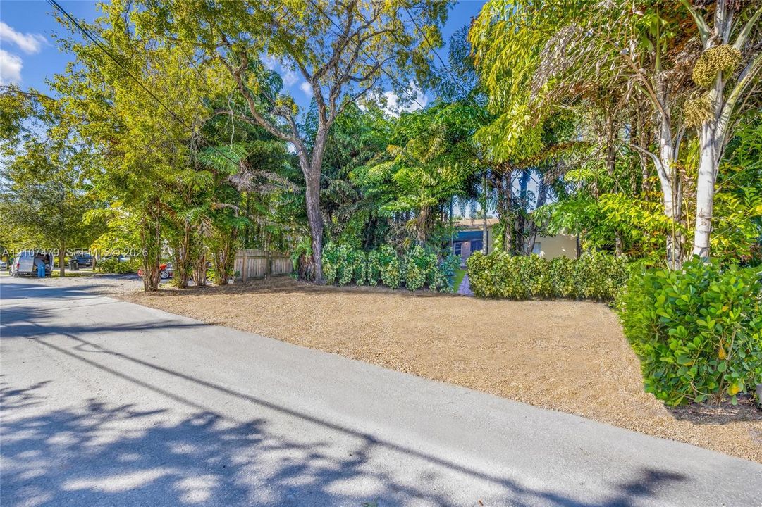 Main house Parking, Level lot featuring mature trees, established shrubbery, and a paved street frontage