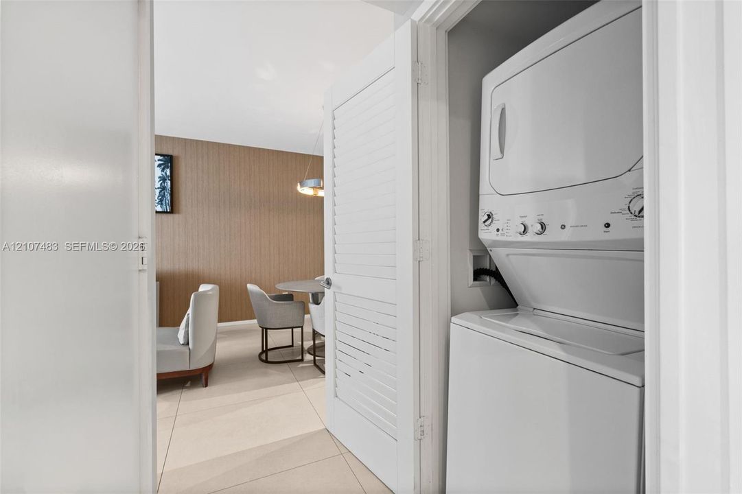 Stackable laundry unit housed behind a louvered closet door
