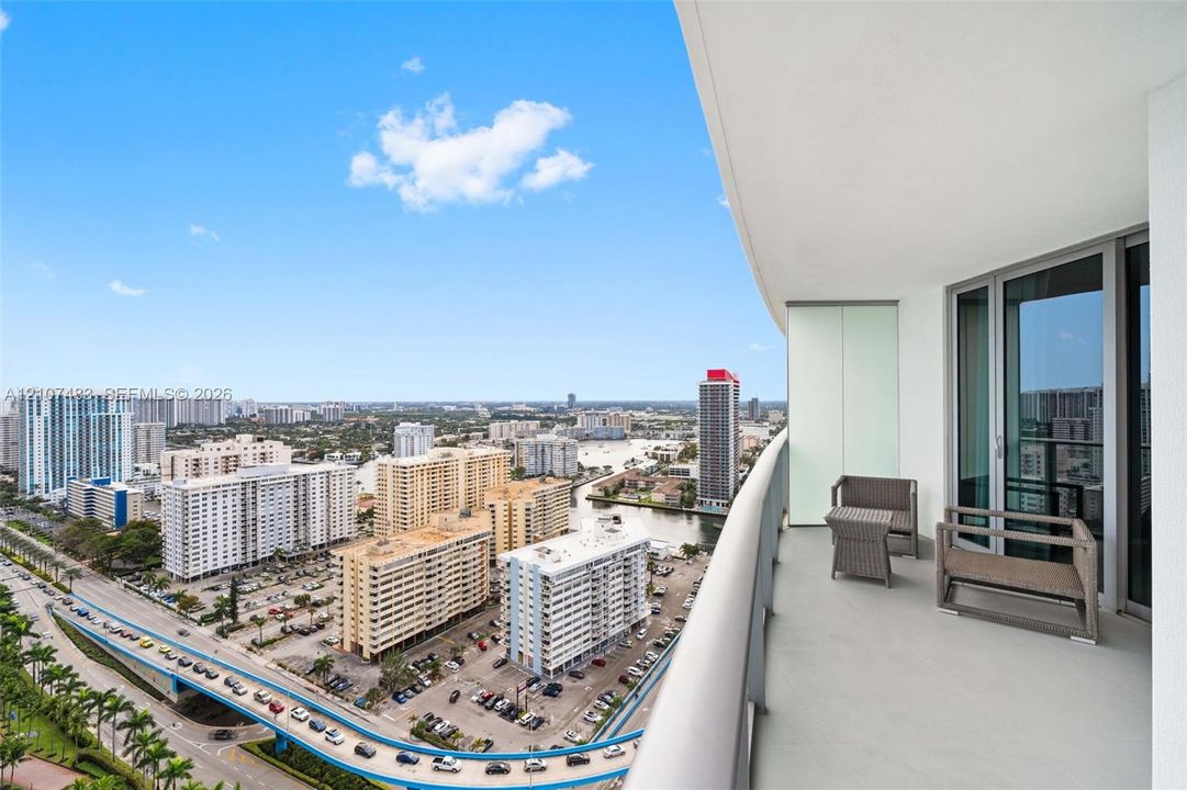 Private balcony with glass and metal railing, concrete flooring, and floor-to-ceiling glass entry doors