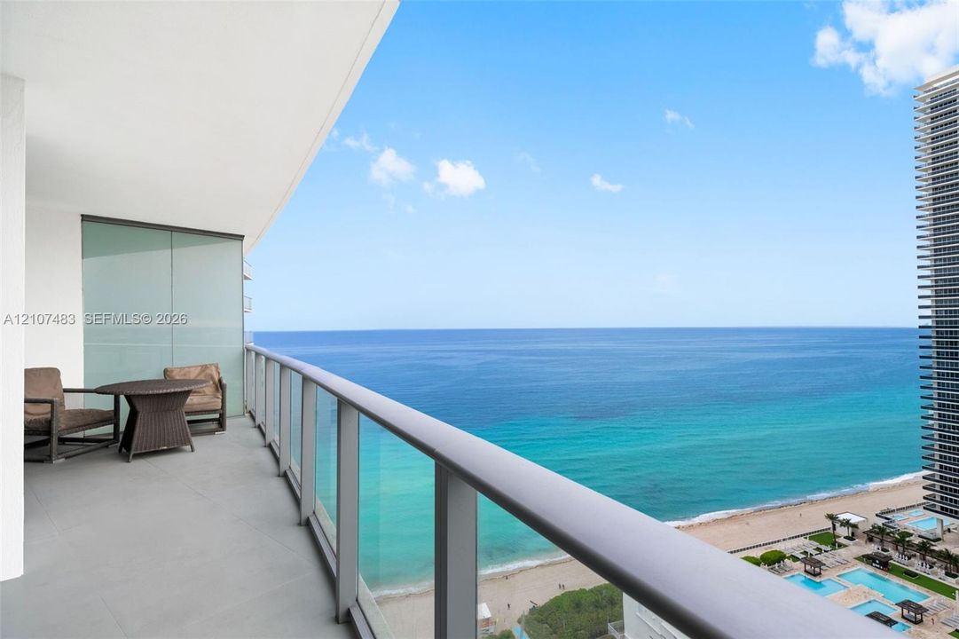 Private balcony featuring neutral-toned tile flooring, minimalist metal railings, and clear glass panels