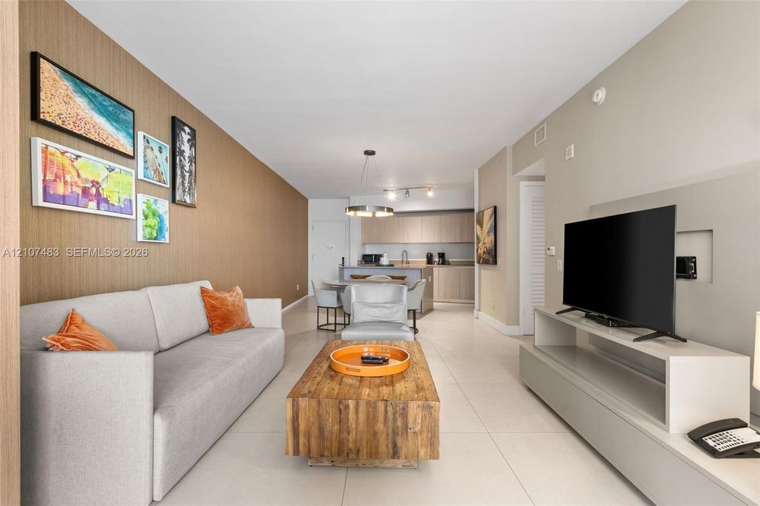 Open concept interior featuring large-format tile flooring, a textured accent wall, and recessed media wall shelving