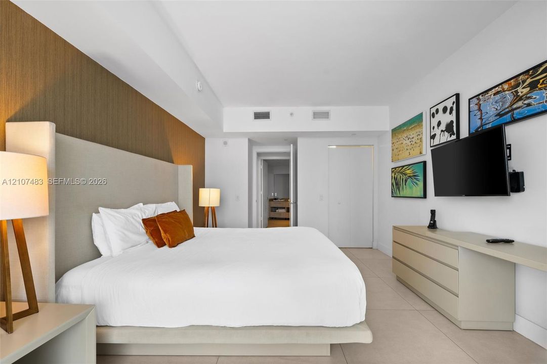 Spacious room featuring a floor-to-ceiling accent wall, tile flooring, built-in cabinetry with an integrated desk surface, and neutral wall tones